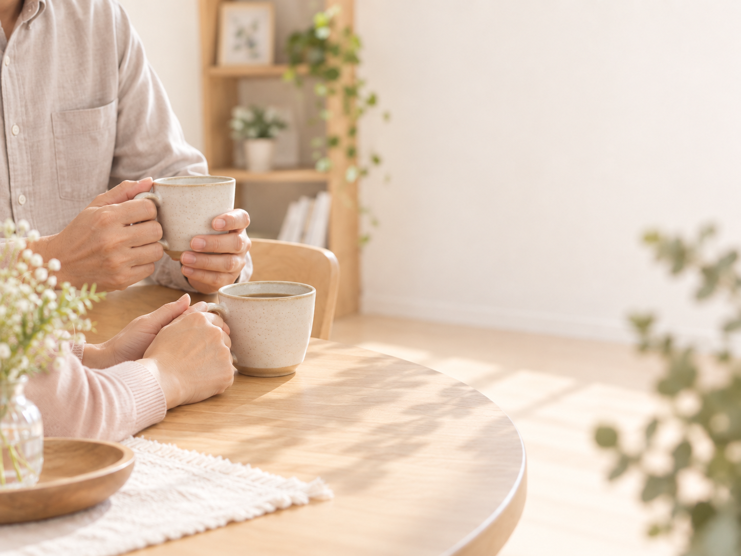 明るい室内で、カップを手に向き合う二人の手元のイメージ